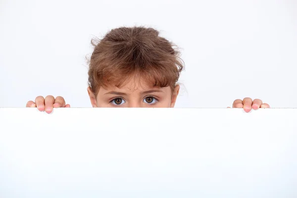 Girl peeking above a board — Stock Photo, Image