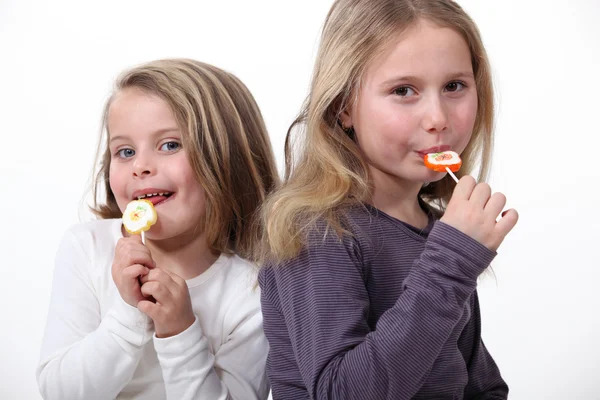 Two sisters eating lollipops. — Stock Photo, Image