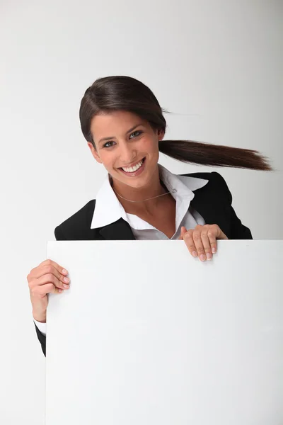 Jonge lachende vrouw in een pak met een bord leeg voor uw bericht — Stockfoto