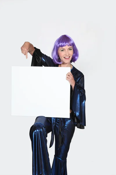 Donna in costume anni Settanta e parrucca in possesso di bordo vuoto — Foto Stock