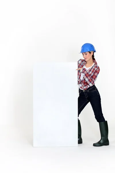 Kvinnlig byggmästare pekar på affisch — Stockfoto