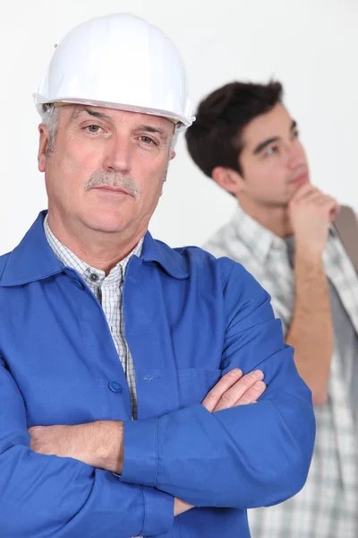 En byggnadsarbetare och hans trainee. — Stockfoto