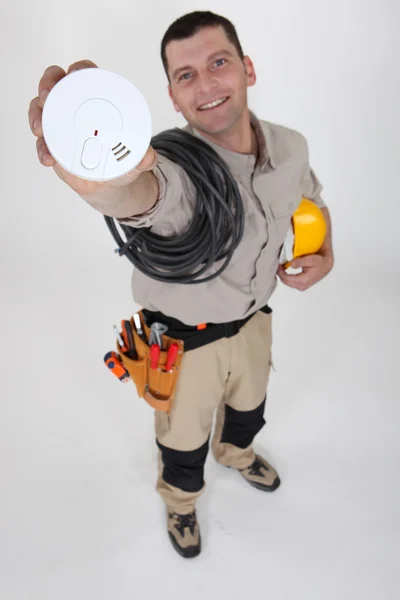 En elektriker som håller en brandvarnare. — Stockfoto