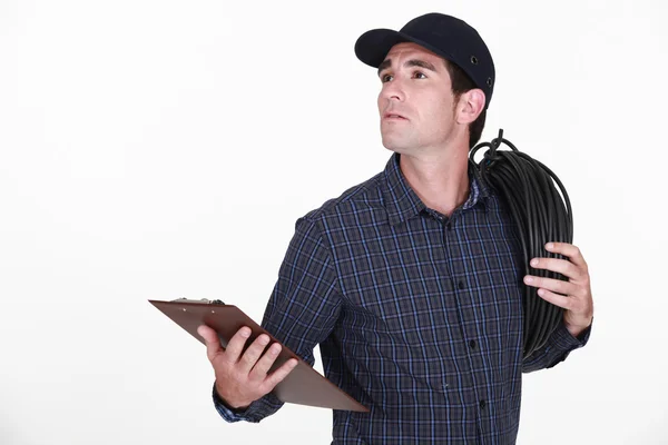 Electrician carrying extension lead with clipboard — Stock Photo, Image