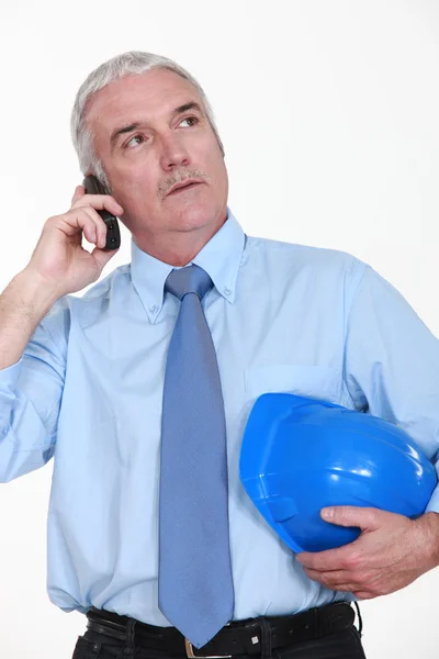 Hombre de negocios mayor sosteniendo un casco y hablando en su celular — Foto de Stock