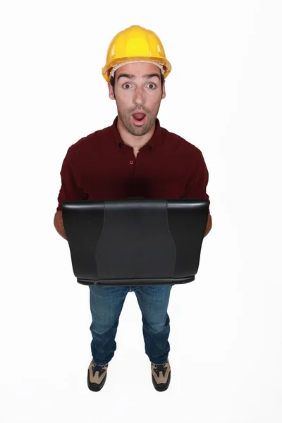 Шокований будівельник тримає ноутбук — стокове фото