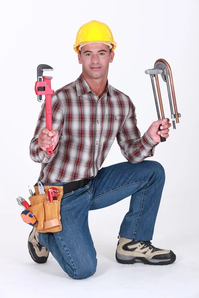Portrait of a plumber with tools in both hands — Stock Photo, Image