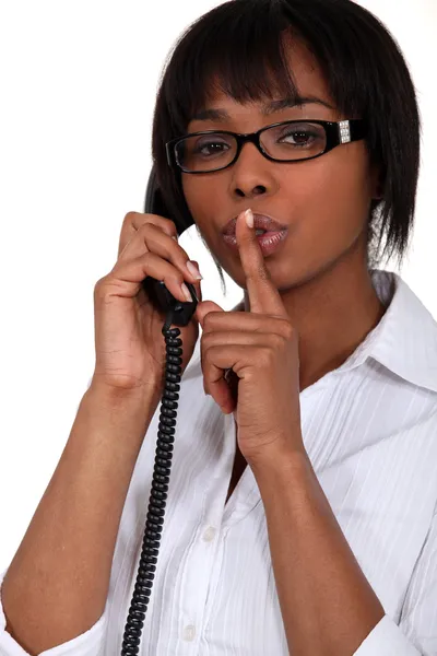 Mulher falando ao telefone e segurando o dedo nos lábios — Fotografia de Stock
