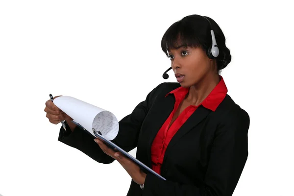 Donna d'affari nera con auricolare che tiene appunti — Foto Stock