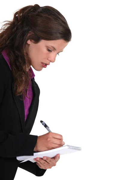 Brunhårig kvinna skriver på ett anteckningsblock — Stockfoto