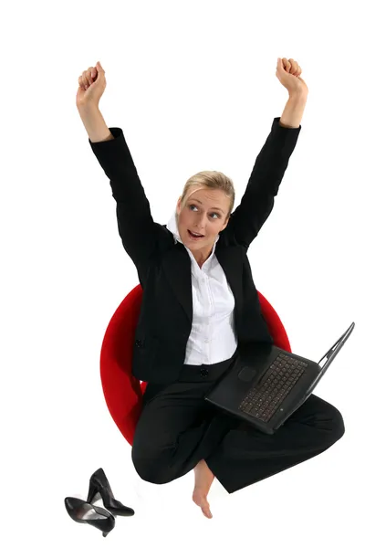 Бізнес-леді сидить на стільці зі своїм ноутбуком і піднімає руки — стокове фото