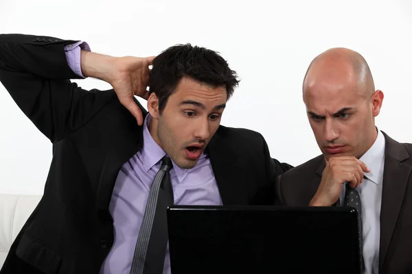 Dois trabalhadores de escritório chocados segurando laptop — Fotografia de Stock