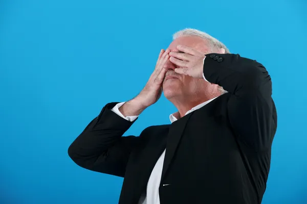 Senior affärsman som täcker hans ögon med händerna — Stockfoto