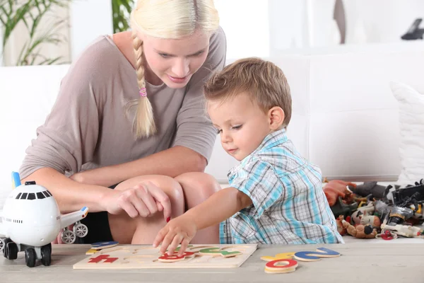 Little boy and young woman playing to puzzle — Stock Photo, Image