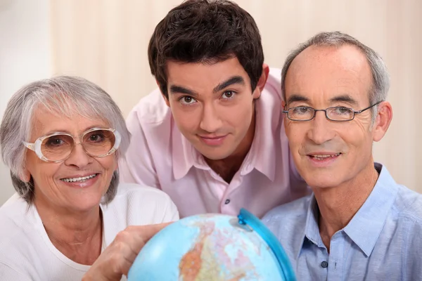 Grown-up family looking at a globe — Stock Photo, Image