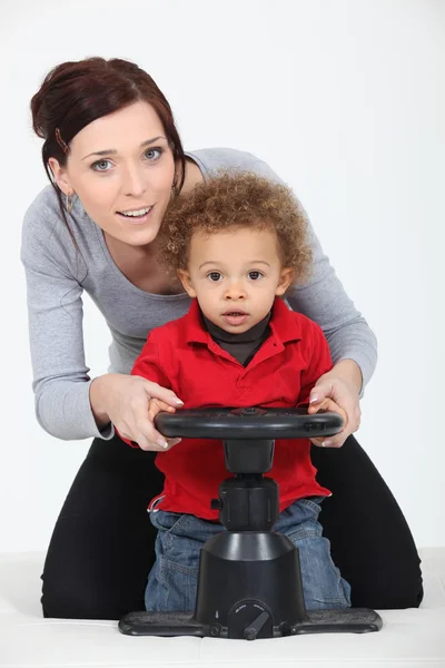 A mother and her son playing with a steering wheel — Stock Photo, Image