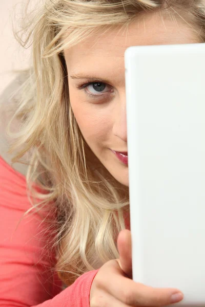 Blondine versteckt Gesicht hinter Laptop — Stockfoto