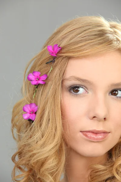 Jovem com flores cor-de-rosa no cabelo — Fotografia de Stock