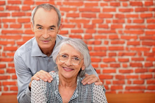 Älteres Paar vor einer Ziegelmauer — Stockfoto