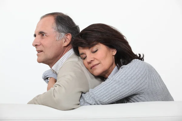 Пара средних лет обнимается на диване . — стоковое фото