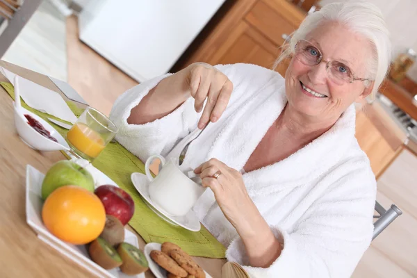 Elderly woman having breakfast — Stock Photo, Image
