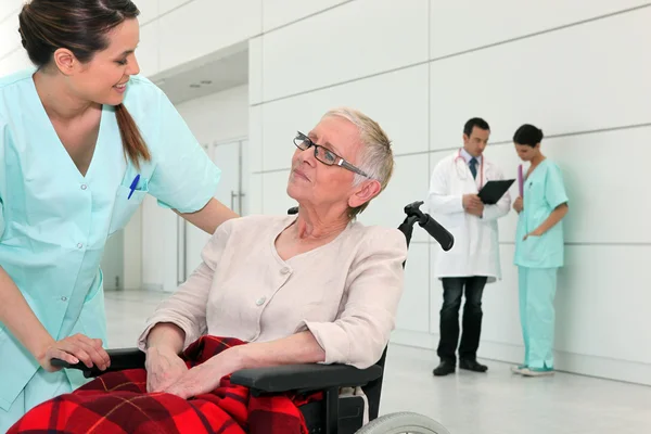 Sjuksköterska talar att en äldre kvinna i rullstol — Stockfoto