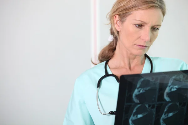 Verpleegster kijkt naar röntgenfoto — Stockfoto