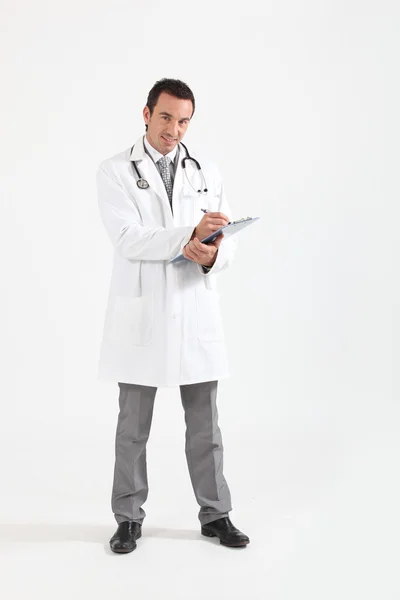 Dokter aan het schrijven op klembord glimlachend — Stockfoto