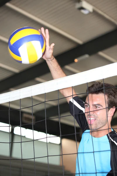 Um jogador de voleibol acertando a bola sobre a rede . — Fotografia de Stock