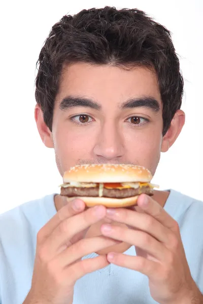 Jeune homme face à un hamburger Image En Vente