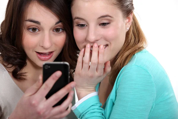Two girlfriends looking at a cell and laughing — Stock Photo, Image