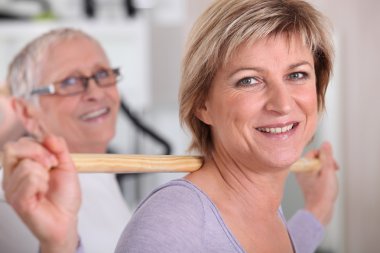 Woman using a wooden stick in a gym clipart