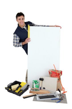 Tile fitter posing with his tools, building materials and a blank sign clipart