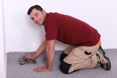 Man on all fours stapling carpet clipart