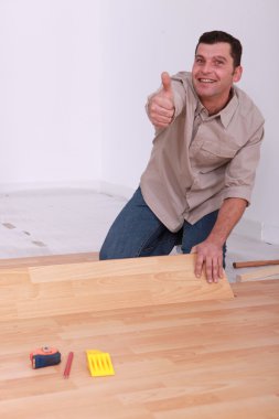 Man laying wooden flooring at home clipart