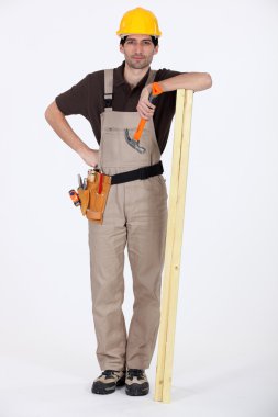 Man stood with plank of wood and hammer clipart