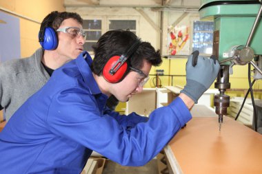 Young man learning how to use a drill press clipart