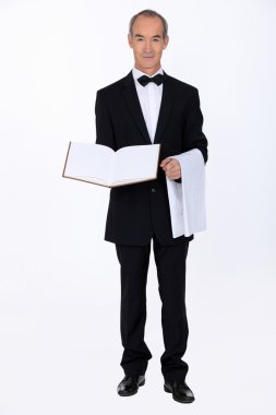 60 years old well dressed waiter is presenting a visitor book or a menu clipart