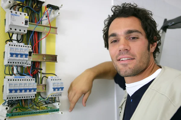 Jovem eletricista posando perto do medidor elétrico — Fotografia de Stock