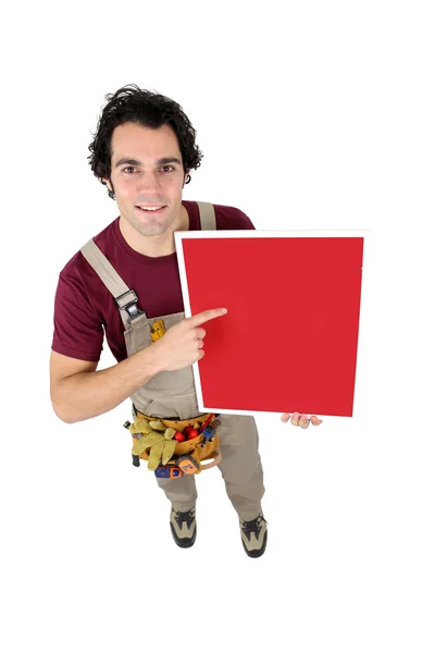 Handyman pointing to a red sign — Stock Photo, Image