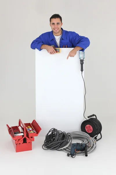 Electricista apuntando a un tablero dejado en blanco para su mensaje —  Fotos de Stock