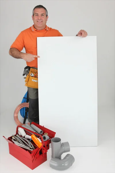 Encanador com materiais e uma placa deixada em branco para sua mensagem — Fotografia de Stock