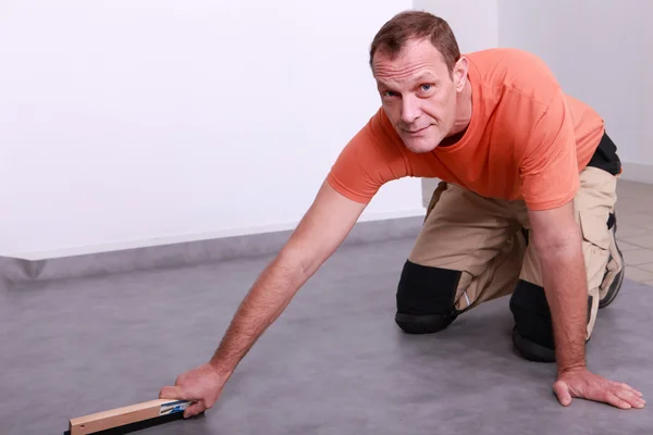 Homem alisamento piso de linóleo — Fotografia de Stock