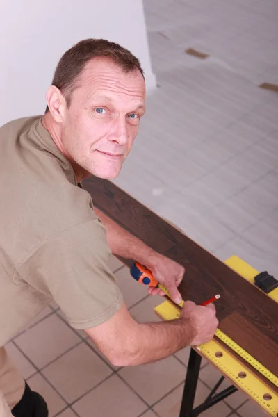 Homem que mede piso laminado — Fotografia de Stock