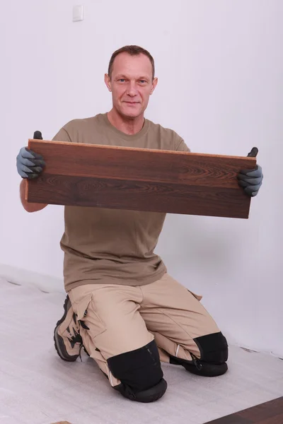 Man holding up a wooden plank — Stock Photo, Image