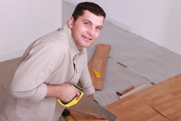 Ένας άνθρωπος πριόνισμα ξύλινα floorboards — Φωτογραφία Αρχείου