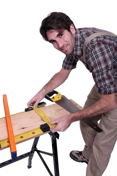 Carpintero midiendo madera en un banco de trabajo — Foto de Stock