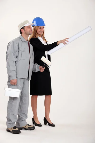 Um pintor e uma mulher trabalhadora conferindo — Fotografia de Stock
