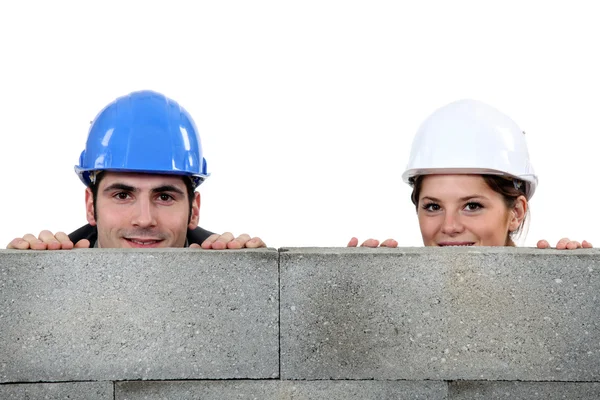 煉瓦工の男性と女性の同等の壁の後ろに隠れて — ストック写真