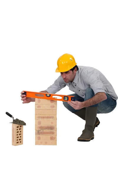 Un albañil revisando una pila de ladrillos con su nivel . —  Fotos de Stock